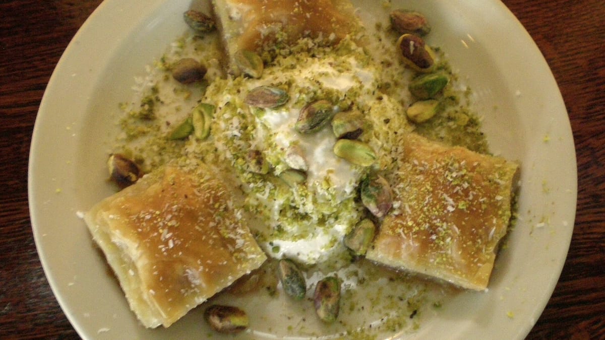 Baklava-Stücke mit Pistazien und Sahne auf einem Teller