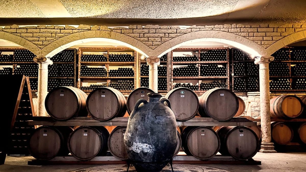 Amphore und Barriquefässer im Gewölbekeller von Çobo Winery, umgeben von historischem Mauerwerk