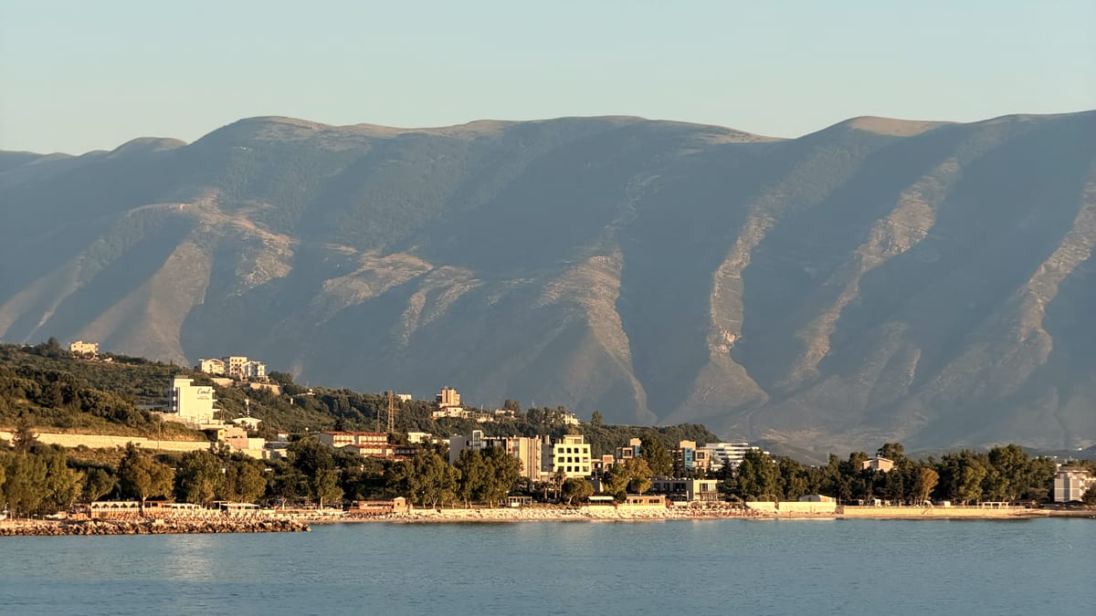 Albanische Küstenstadt am Fuß grüner Berge im goldenen Abendlicht bei Vlora