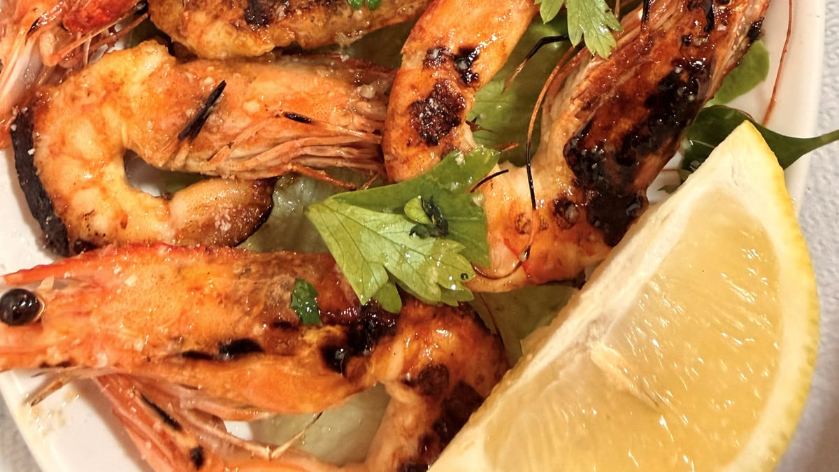 Gegrillte Garnelen mit Zitrone und Kräutern auf einem Teller