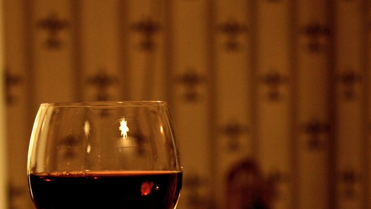 Ein Glas Rotwein im warmen Kerzenlicht auf einem gedeckten Tisch