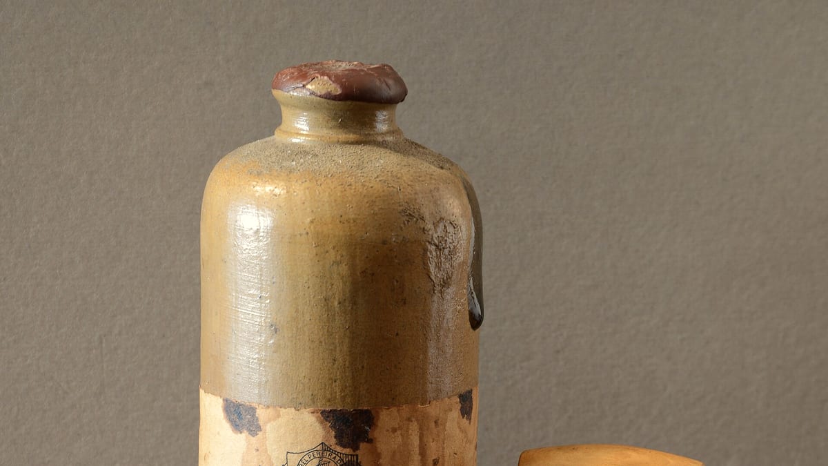 Eine alte, mit Kork verschlossene Weinflasche aus Steingut auf einem Holztisch